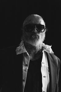 Portrait of man wearing sunglasses against black background