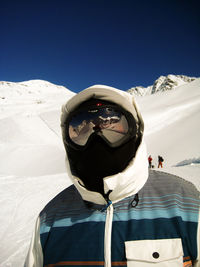 Person wearing ski goggles standing on snow covered land