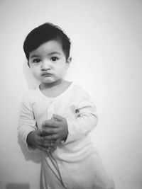 Portrait of cute boy looking away while standing against white wall