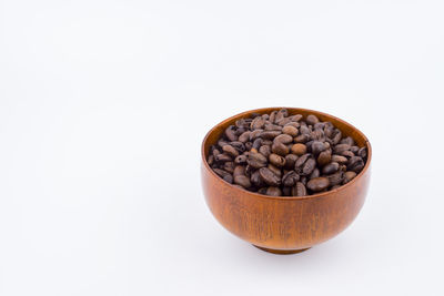 Close-up of coffee beans in bowl against white background