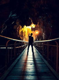 Man standing on footbridge at night