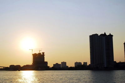 Modern buildings in city against sky during sunset