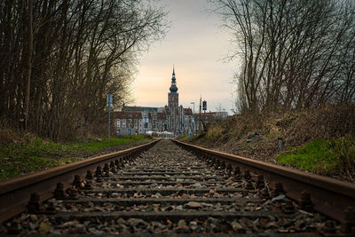 Railroad tracks by bare trees against sky