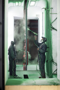 Painters spraying steel components in spray booth of a factory