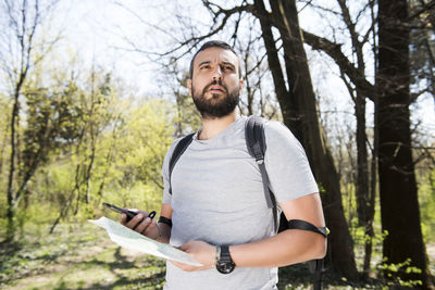 Hiker holding map while standing in forest