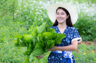 Portrait of a smiling young woman standing against plants