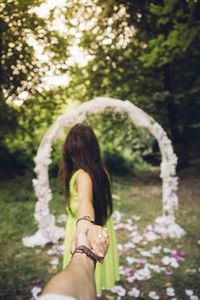 Midsection of woman with pink flowers against trees