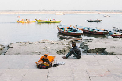 Rear view of men sitting on boat moored at sea