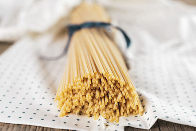 Group of uncooked italian spaghetti pasta tied together by blue silk ribbon on cloth background