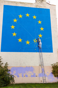 Low angle view of flag against blue wall