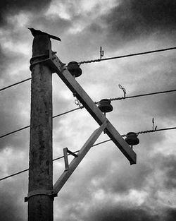 Low angle view of power lines against cloudy sky