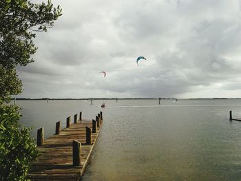 Pier on lake against cloudy sky