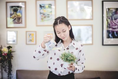 Portrait of woman holding flower at home