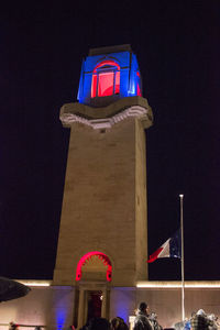 Low angle view of flag against building at night