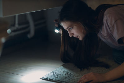 Side view of young woman sitting on floor at home