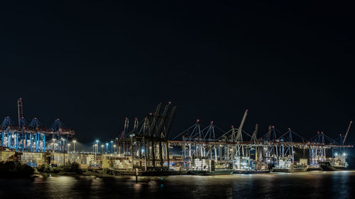 Illuminated bridge over river against sky at night