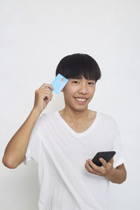 Portrait of smiling young woman using smart phone against white background