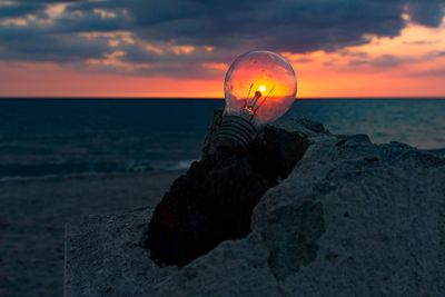 Close-up of rock on beach against sky during sunset