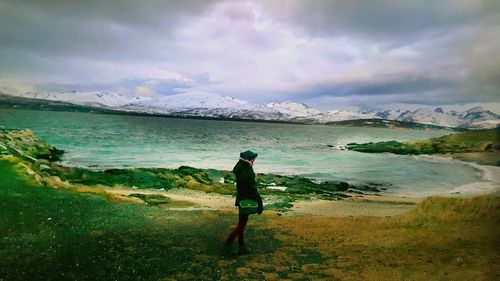 Rear view of man standing on shore against sky