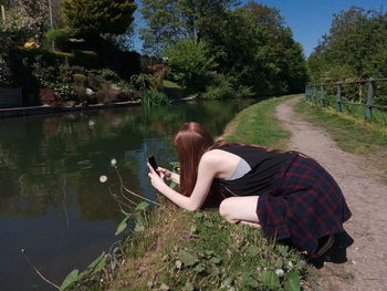 Woman using mobile phone by lake