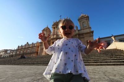 Low angle view of cute baby girl wearing sunglasses while standing against church