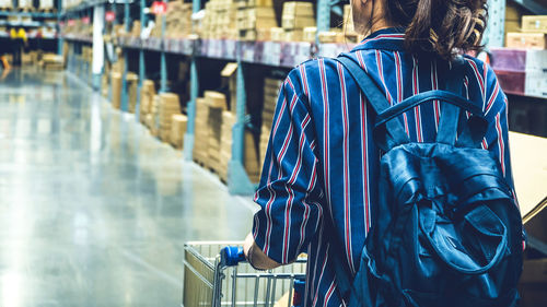 Midsection of woman with shopping cart walking in supermarket