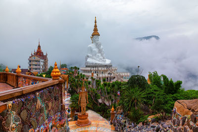 Statue amidst trees and buildings against sky