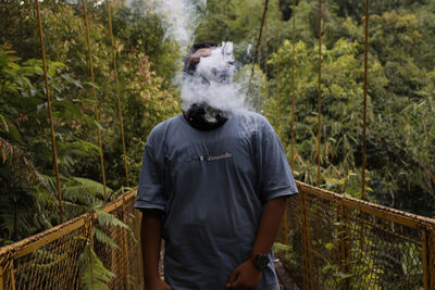 Man smoking against trees in forest