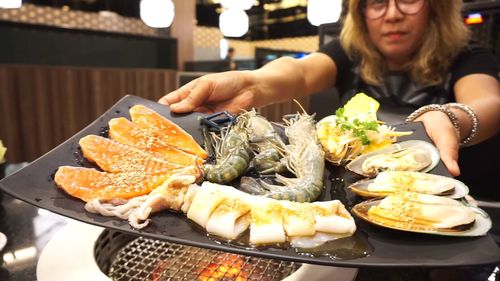 Woman offering food while sitting at restaurant