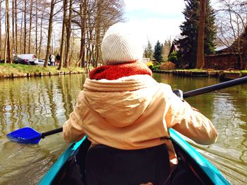 Rear view of people sitting on boat in river