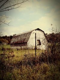 Abandoned house on field against sky