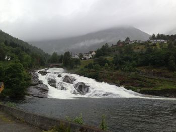 Scenic view of river by mountains against sky