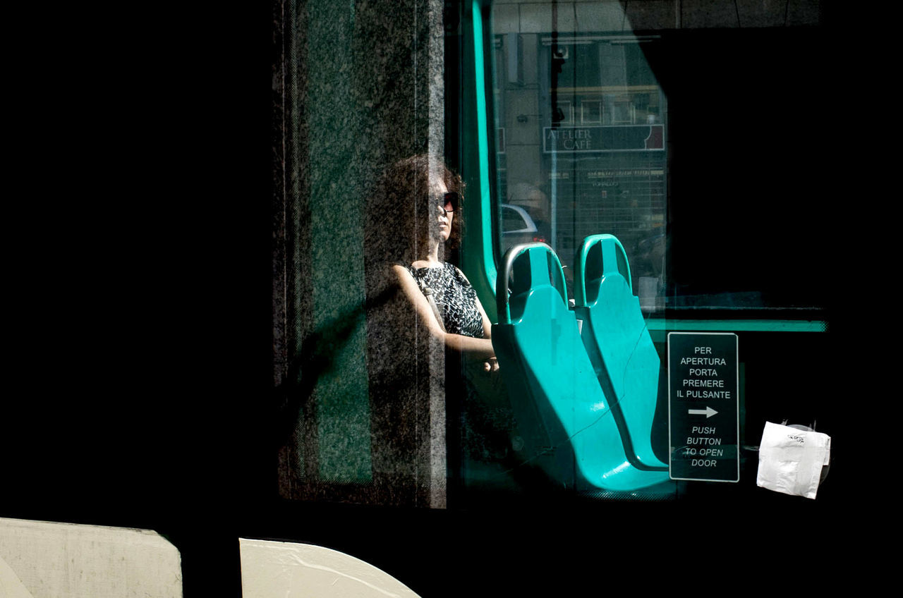 one person, real people, green color, window, lifestyles, mirror, adult, leisure activity, technology, communication, sunlight, women, day, wall - building feature, dark, glass - material, transparent, looking, indoors