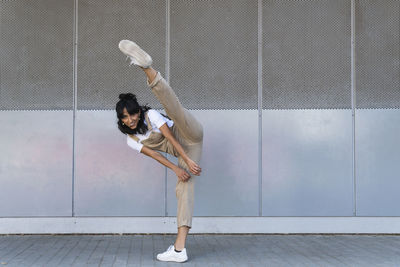 Smiling woman kicking on footpath