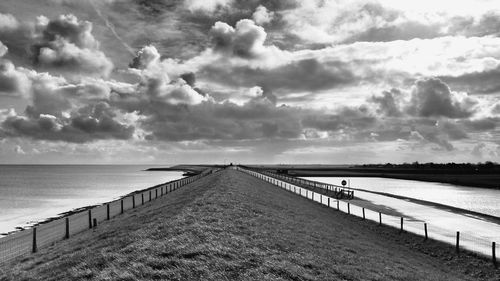 Pier on sea against cloudy sky