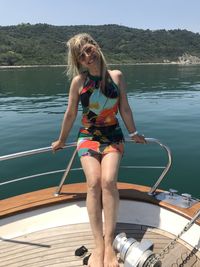 Full length portrait of smiling woman standing on boat