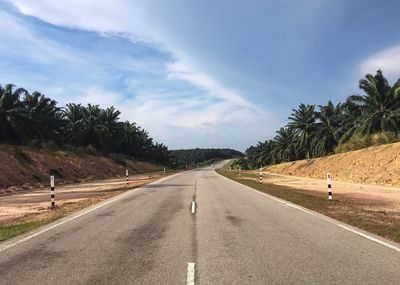 Road by trees against sky
