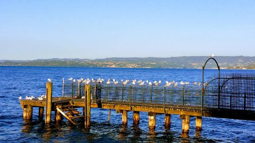 Pier over sea against clear blue sky