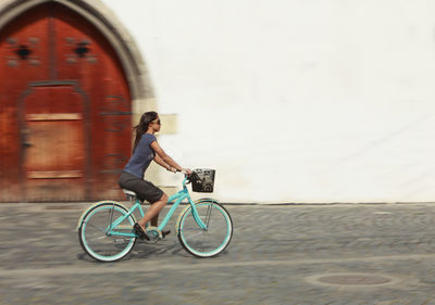 Woman riding bicycle on road in city