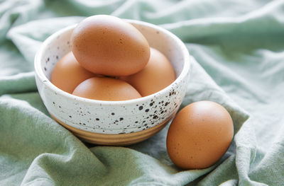 Bowl of fresh brown eggs on concrete background