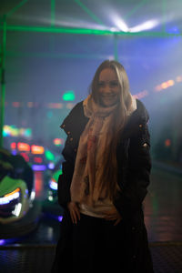 Woman standing against illuminated building at night