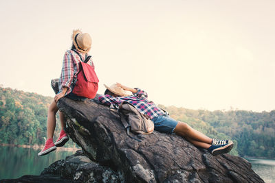 Friends sitting on rock at lakeshore