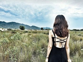 Rear view of woman standing on landscape against sky