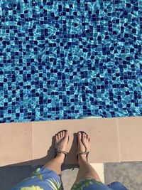 Low section of woman standing by swimming pool