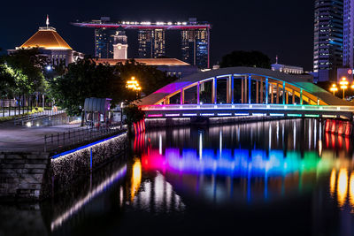 Illuminated bridge over river in city at night