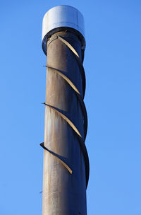 A large brown chimney on industrial building with spiral metal