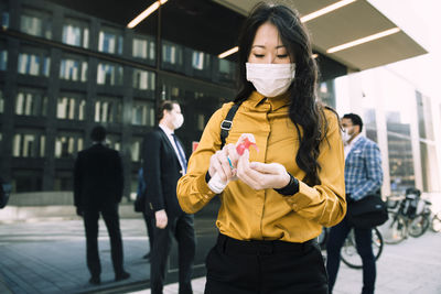 Woman with face mask using hand sanitizer