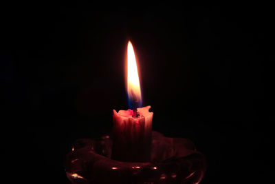 Close-up of burning candle against black background