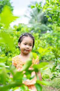 Thoughtful girl standing amidst plants