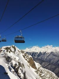 Overhead cable car over snowcapped mountains against clear sky